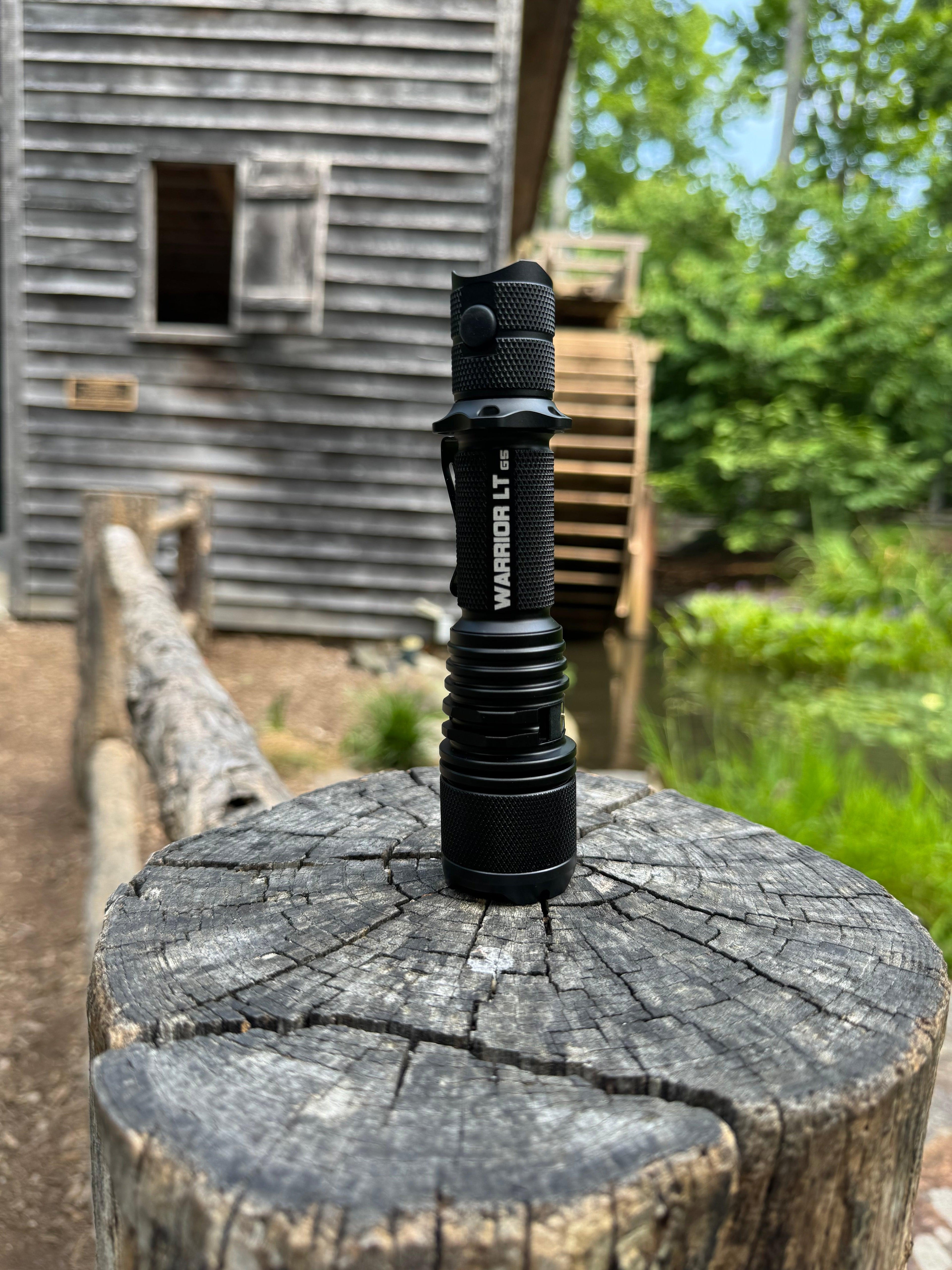 Powertac Warrior Gen5 LT tactical flashlight on wooden post – Powertac vs COAST comparison at Lumex Flashlights