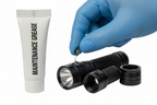 A black flashlight shown disassembled with its cap removed, alongside a white tube labeled 'MAINTENANCE GREASE' and a blue-gloved hand holding a small metal ring over the flashlight on a white background.