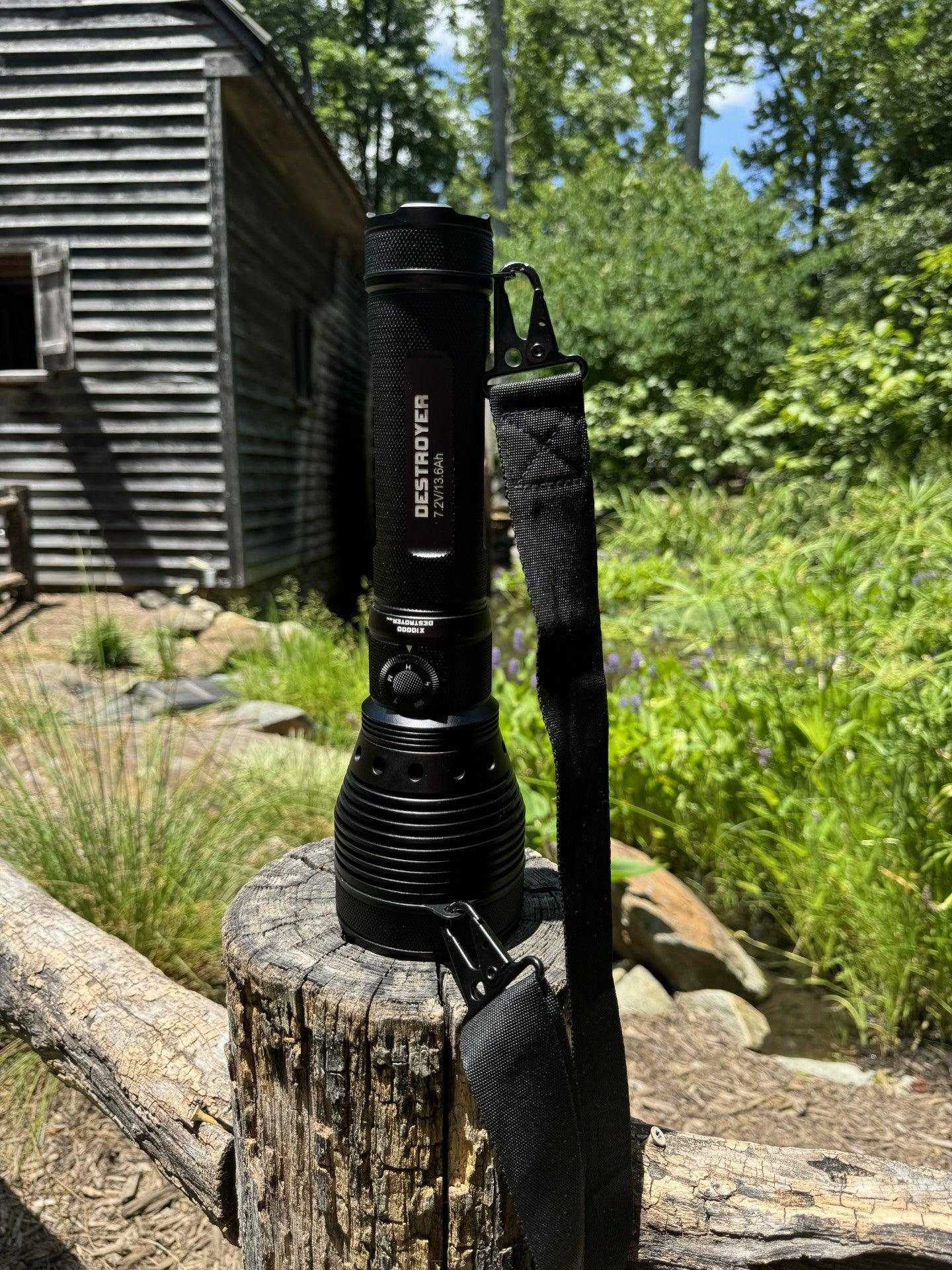 Black flashlight on a log with a cabin and trees in the background