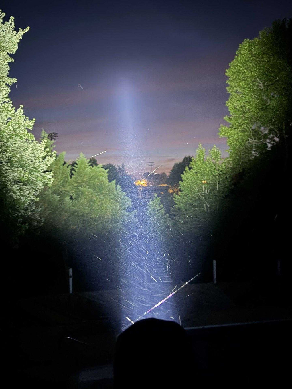 Light beam through trees at night with a distant light source